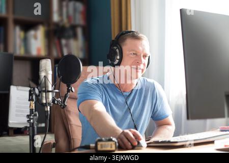 Man nimmt Kopfhörer vor dem Mikrofon auf und nimmt Podcast auf dem Computer im Heimstudio auf. Massenmedien Stockfoto