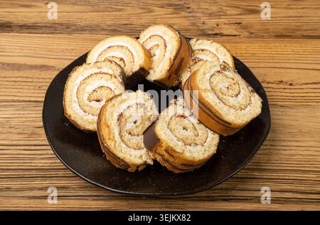 Schweizer Rolle, Runde Schwammkuchen, geschnittener gerollter Vanillekeks mit Marmelade Füllung, Schweizer Dessert, Blockkuchen auf hölzernem Hintergrund Stockfoto
