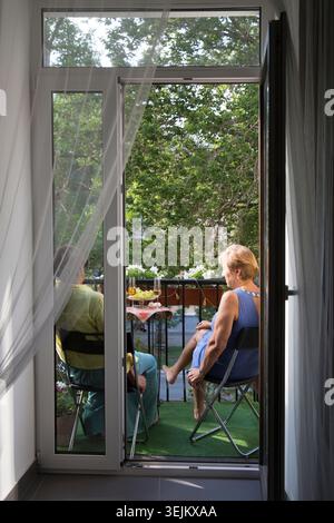 Porträt glücklicher Seniorinnen, die auf einem Balkon der Wohnung sitzen und reden Stockfoto