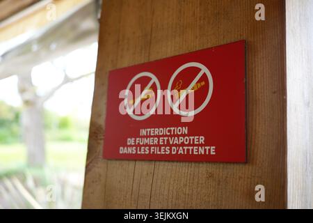 Kein Rauchen und kein Dampfschild auf Französisch an einem Holzpfosten in einem öffentlichen Warteschlangenbereich. Stockfoto