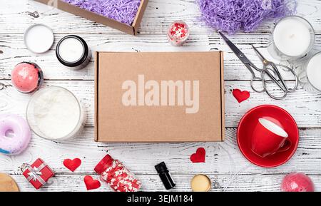 Saisonale Geschenkbox zum valentinstag mit Kerze, roter Tasse und süßen Süßigkeiten in Herzform Stockfoto
