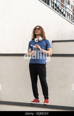 Selbstbewusster, sportlicher Mann, der in urbaner Umgebung auf der Kante steht Stockfoto