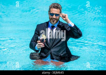 Sommerreise erneuern. Geschäftserfolg. Geschäftsmann im Schwimmbad. Aufgeregter Geschäftsmann im Nassanzug im Schwimmbad. Business Drink Sommer Stockfoto