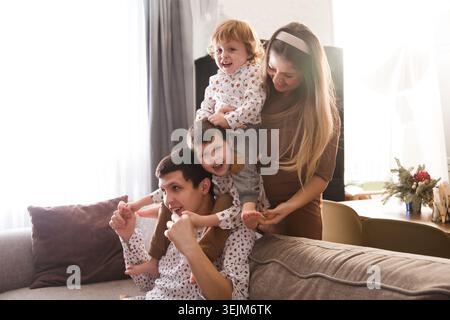 Familie hat Spaß, Zeit zu Hause zusammen zu verbringen. Mom, Dad und zwei Sohn spielen, umarmen und Spaß zu Hause haben. Christm Stockfoto
