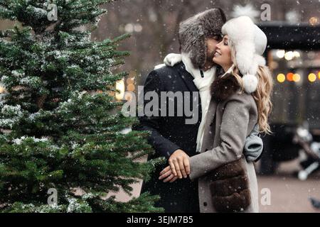 Ein paar Liebhaber umarmen, küssen, stehen auf der Winterstraße bei schneebedecktem Wetter. Valentinstag Stockfoto