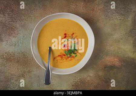 Kürbiscremesuppe, in einer weißen Schüssel auf strukturiertem Hintergrund, Blick von oben, hausgemacht, keine Leute, rustikaler Stil, Stockfoto