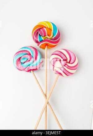 Farblutscher, spiralförmige Süßigkeiten auf Stock, bunt gestreifter Lutscher, rundes Fruchtkaramell, mehrfarbige Süßwaren, kreisförmiger Lutscher auf weißem Hintergrund Stockfoto