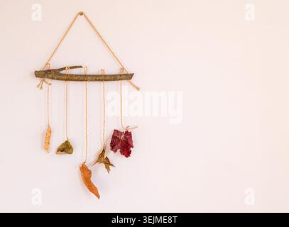 Herbstkomposition von auf Holzstock hängenden bunten Blättern als Element des Wohnraums Stockfoto