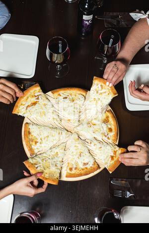 Blick auf Freunde, die Pizza an einem Restauranttisch teilen Stockfoto