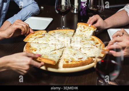 Blick auf Freunde, die Pizza an einem Restauranttisch teilen Stockfoto