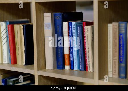 Moskau, Russland - 11. Mai 2026: Sammlung verschiedener Bücher auf Holzregal mit bunten Stacheln und sichtbaren Titeln in verschiedenen Sprachen Stockfoto