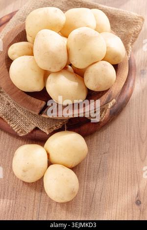 Gekochte neue Kartoffeln, in einer Holzschale, auf einem rustikalen Tisch, natürliches Licht, keine Leute, Stockfoto