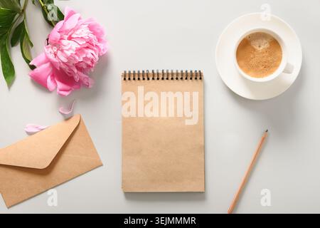 Kreatives weibliches Modell mit Kaffeetasse, Pfingstrosenblüten, Skizzenbuch für die Planung. Stockfoto