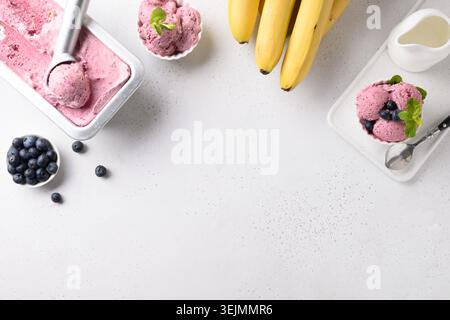 Hausgemachte Banane, Beeren Eis in Metallbehälter und Portion in Schüssel auf weiß. Blick von oben. Leerzeichen für Text. Stockfoto