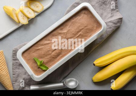 Bananen und Kakao hausgemachtes Eis im Behälter auf Grau. Stockfoto