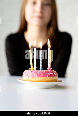 Teenager-Geburtstagskind, das Kerzen auf den Donut bläst Stockfoto