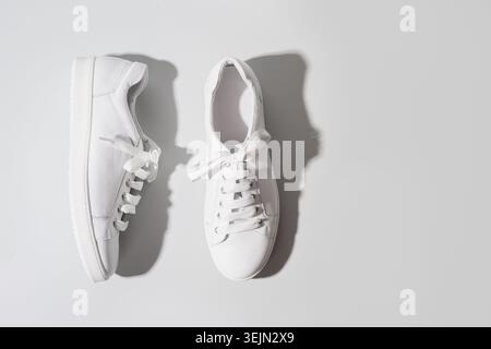 Paar weiße weibliche Sneakers auf Gelb. Flach, Ansicht von oben minimalen Hintergrund. Heftkonzept. Stockfoto