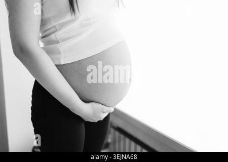 Schwarz-weiße Nahaufnahme des schwangeren Bauches einer jungen Frau Stockfoto