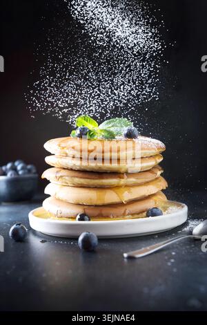 Süßer hausgemachter Stapel Pfannkuchen mit Powerzucker auf Schwarz. Nahaufnahme. Stockfoto