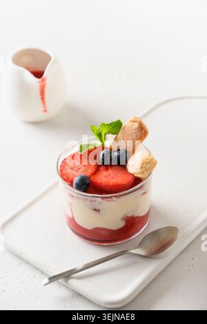 Mehrschichtiges Dessert in Glasgläsern mit Cookie Savoyardi, Mascarpone und Erdbeeren mit Schlagsahne Stockfoto