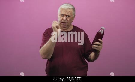 Mann hält eine Flasche Granatapfelsaft, Gesten mit der Hand beim Prüfen der Kappe im Studio; Skepsis Inspektion Gesundheit. Stockfoto