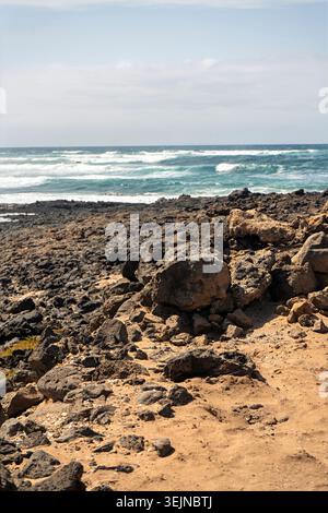 Blick auf das Meer jenseits einer kargen Wüstenlandschaft auf Lanzarote, wo vulkanisches Gelände auf den Horizont trifft und der Atlantik in der Ferne leuchtet Stockfoto