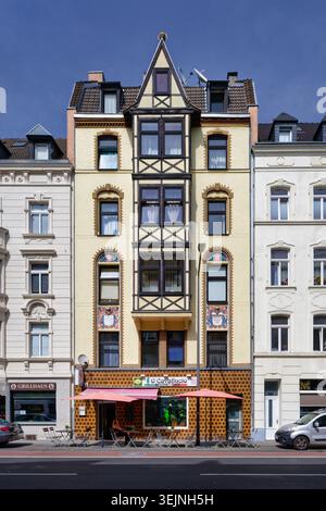 Köln, Deutschland 29. Mai 2026: Schöne Fassade eines historischen Gebäudes in Köln-Ehrenfeld mit Holzfenster, Mosaiken und einem Café im Freien Stockfoto