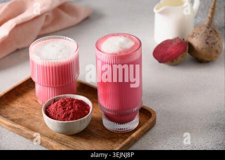 Rote Bete Latte oder rosa Mondmilch Latte in Glasbecher auf grauem Hintergrund. Tolles warmes Getränk. Stockfoto