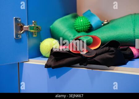 Schließfach im Umkleideraum mit persönlichen Sportwerkzeugen, Tennisball und Kleidung Stockfoto