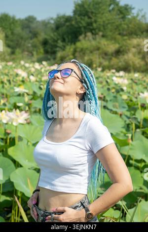 Eine junge Frau mit wunderschönen blauen Dreadlocks, die auf dem Lotussee ruhen Stockfoto