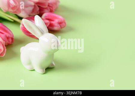 Ostergrußkarte mit Häschen- und Tulpenblüten auf grünem Hintergrund. Stockfoto