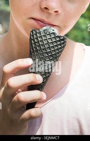 Teen essen schwarzes Eis in schwarzem Waffelkegel Nahaufnahme Porträt Stockfoto