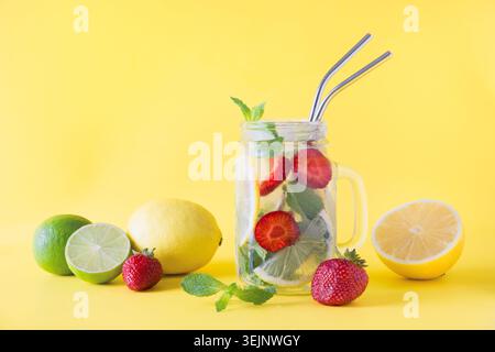 Entgiftungswasser, Limonade oder Mojito mit Zitrone, Limette, Erdbeere im einmachglas auf Gelb. Sommer gesundes Frischgetränk. Platz für t Stockfoto