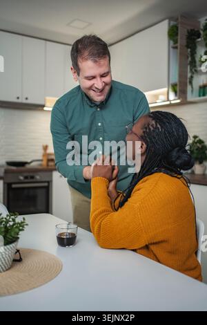 Multiethnisches Paar verbindet Hände, lächelt in der Küche Stockfoto