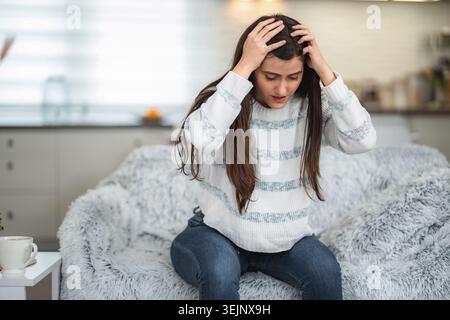 Junge Frau, die zu Hause Stress-Kopfschmerzen hat Stockfoto