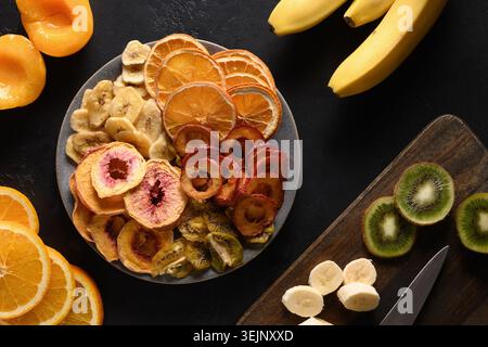 Getrocknete Pflaumen, Kiwi, Pfirsichchips auf Schwarz. Stockfoto