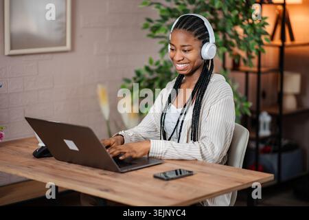 Junge schwarze Frau, die von zu Hause aus mit einem Laptop arbeitet Stockfoto