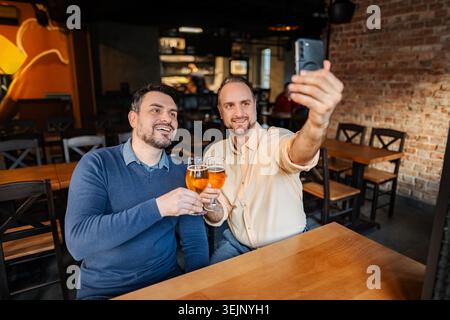 Zwei Männer nehmen Selfie und toasten Bier in einem Pub Stockfoto