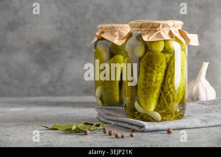 Konservierte Gemüsegurke in Glasgläsern auf grauem Hintergrund. Stockfoto