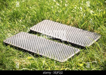Ein Paar Holzbretter mit Metallnägeln für Stehmeditation und Körperübungen auf Rasenflächen im Freien, Wellness- und Achtsamkeitskonzept. Stockfoto