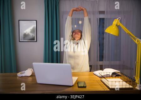 Gesunder Lebensstil der Senioren. Arbeiten Sie von zu Hause aus. Online-Schulung. Ältere Frau kommuniziert am Abend zu Hause online auf einem Laptop Stockfoto