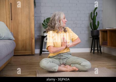 Eine ältere Frau macht Dehnübungen oder Yoga zu Hause. Gesunder Lebensstil. Sport zu Hause Stockfoto