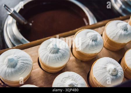 Vanilleeis in Waffelbechern an der Produktionslinie Stockfoto