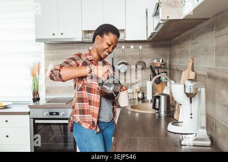 Junge Frau gießen Kaffee in der Küche Stockfoto