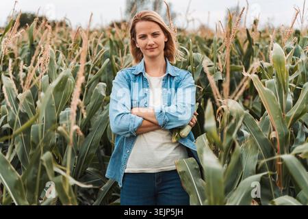 Landwirt steht mit gekreuzten Armen auf dem Maisfeld Stockfoto