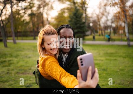 Verschiedene beste Freunde machen Selfie, lachen im Park Stockfoto