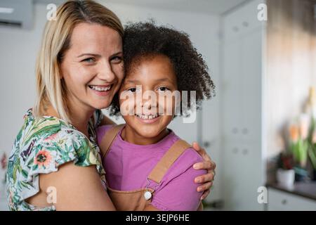 Eine glückliche Mutter, die eine Tochter mit einer Vielfalt umschließt, die Liebe und familiäre Bindung zeigt Stockfoto