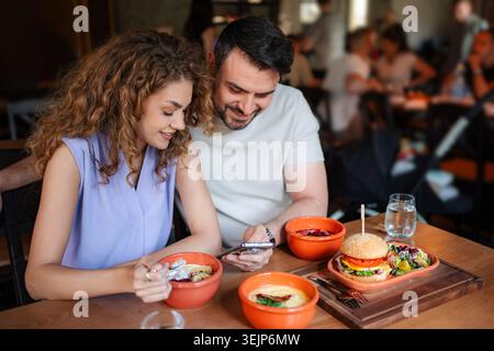 Paare, die beim Mittagessen in einem Restaurant auf das Smartphone schauen Stockfoto