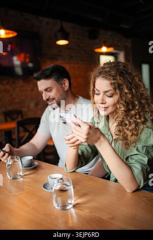 Junges Paar, das Smartphones benutzt, während er Kaffee in einem Café trinkt Stockfoto