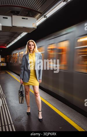 Frau, die auf U-Bahnsteig steht, mit vorbeifahrendem Zug Stockfoto